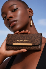 Michael Kors Jet Set Large Logo Trifold Wallet in brown signature PVC leather. Dive deeper in AI Mode