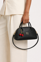 Miu Miu Aventure nappa leather top-handle bag with a cherry bag charm.