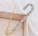 a rhinestone safety pin brooch, often featuring a robust metal base adorned with sparkling crystals.