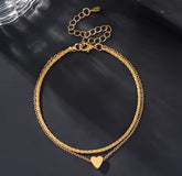 This is a minimalist, gold-plated double-layer ankle bracelet featuring a delicate heart charm and a shimmering chain.