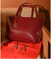 Armani Exchange brand-embossed tote bag in a dark red color and a patent finish.