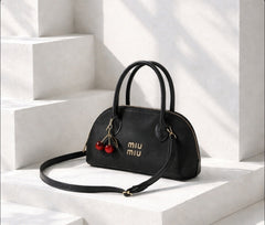 Miu Miu Aventure nappa leather top-handle bag with a cherry bag charm.