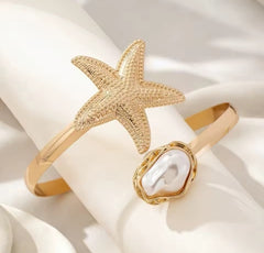 This gold-plated starfish and pearl arm cuff bracelet is often marketed as a boho beach statement piece.
