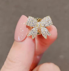 a fashion lapel pin designed as a sparkling rhinestone bowknot brooch.