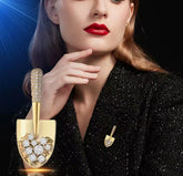 This item is a gold-colored brooch shaped like a shovel, adorned with sparkling crystals.