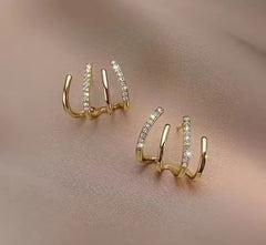 a pair of gold-plated, four-claw cubic zirconia ear cuff earrings.