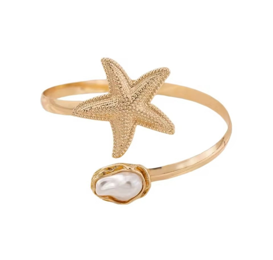 This gold-plated starfish and pearl arm cuff bracelet is often marketed as a boho beach statement piece.