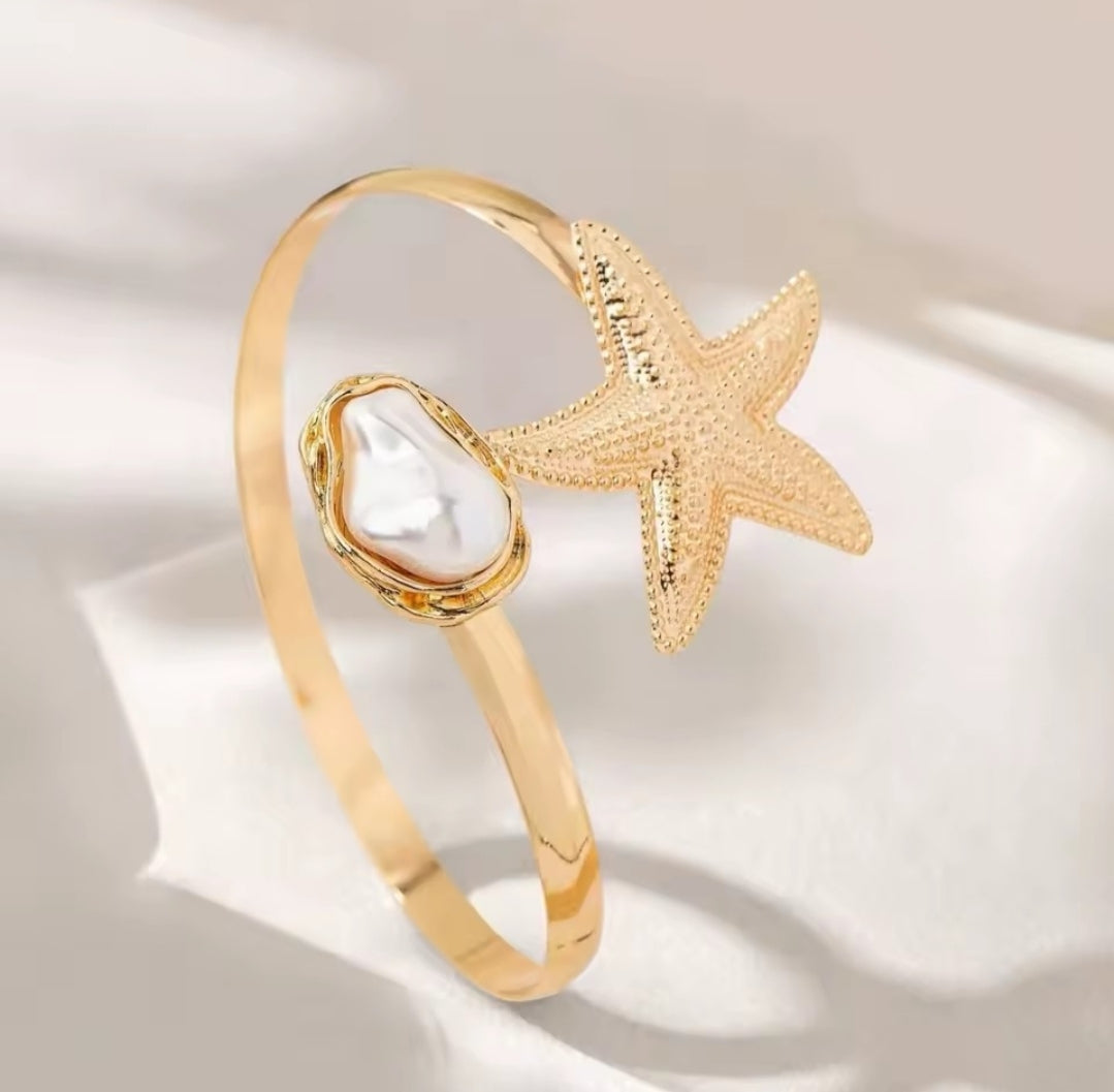 This gold-plated starfish and pearl arm cuff bracelet is often marketed as a boho beach statement piece.