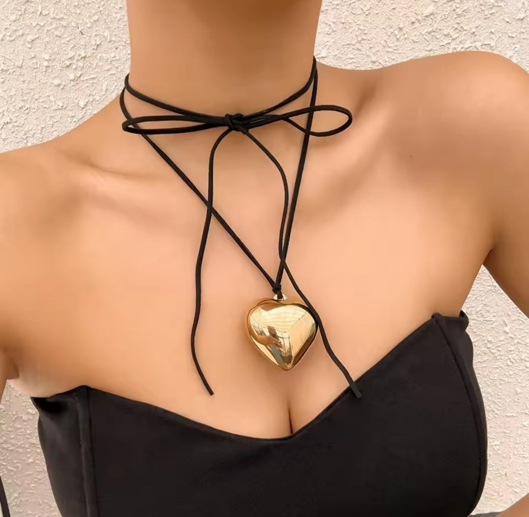 This necklace is an adjustable choker featuring a prominent gold-toned puffy heart pendant