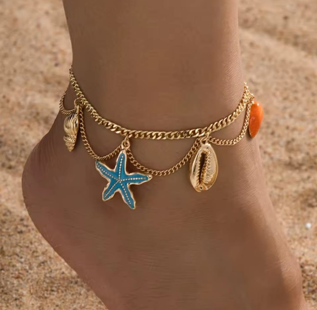 This is a gold-toned, multi-layer women's anklet featuring starfish and shell charms. 