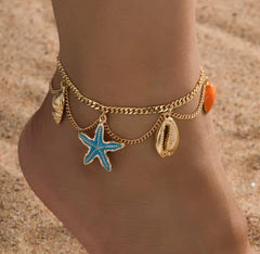This is a gold-toned, multi-layer women's anklet featuring starfish and shell charms. 