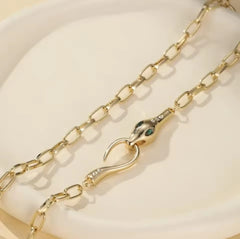 This is a gold-plated snake pendant necklace with green eyes. 